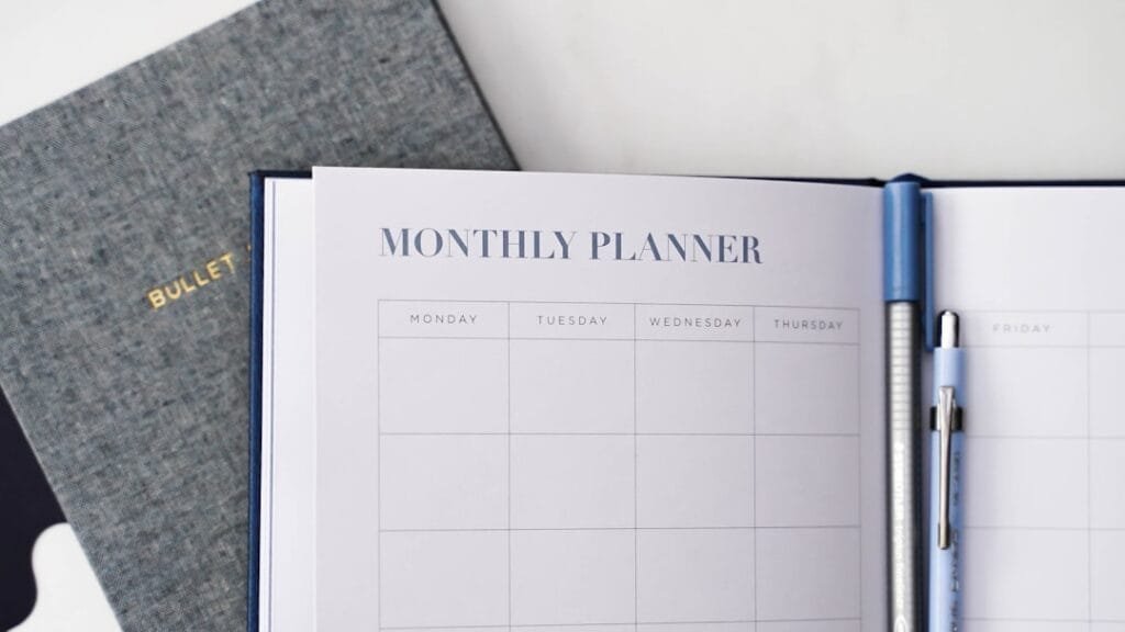 Monthly planner open on desk with pen, representing 30-day job search strategy planning