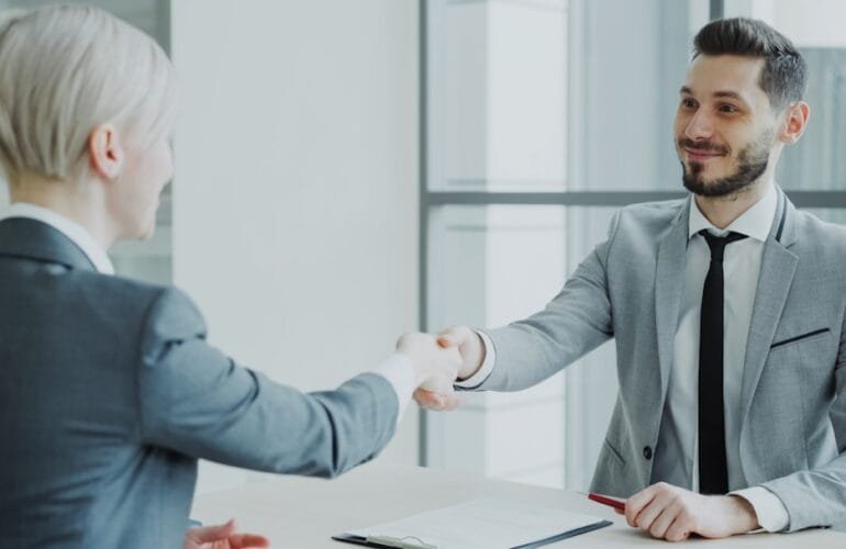 Professional job interview handshake between HR manager and candidate in modern office - Photo by Unsplash